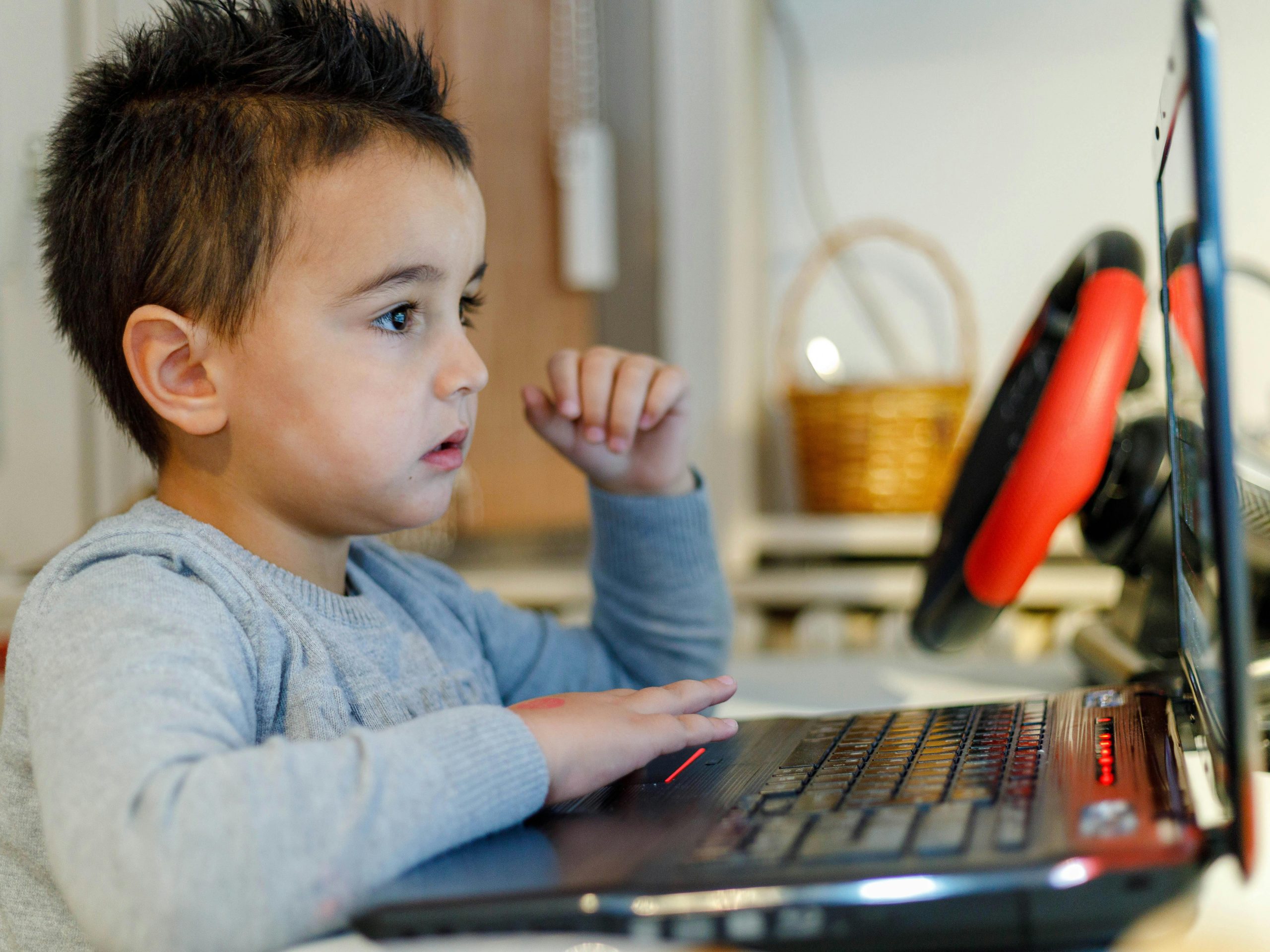A young child focuses intensely on a laptop screen while learning from home, showcasing modern education.