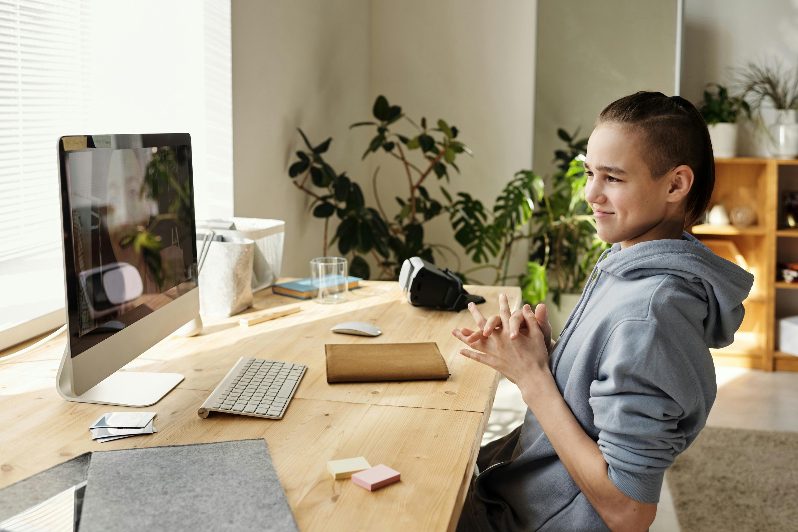 Teenager enjoying a study session with a computer at home, smiling and focused.